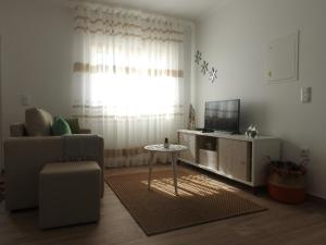 a living room with a couch and a table and a television at Aldeia na Praia - Vale Furado in Pataias