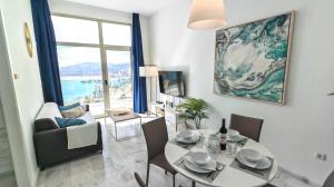 uma sala de estar com uma mesa, cadeiras e um sofá em Highest penthouse with best skyline & sea views em Benidorm