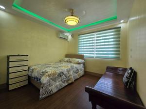 a bedroom with a bed and a table and green lights at Family Friendly House in Malolos