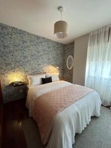 a bedroom with a large white bed and a wall at Apartamento Galeguiña in Vigo