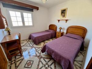 a bedroom with two beds and a table and a window at Casa Pancha in Arinaga
