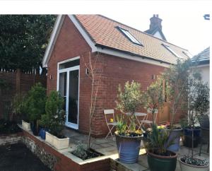 a small brick house with potted plants in front of it at The Coach House, GUILDFORD in Guildford
