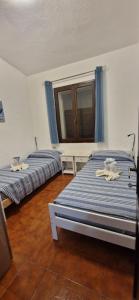 Un dormitorio con dos camas y una ventana. en Villa Elisa, en Villasimius