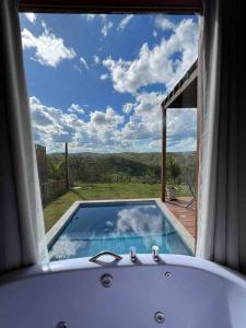 a bath tub in a room with a view at OKA VIVAH - Chalé Oka da Montanha in Jaboticatubas