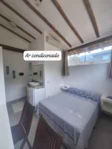 a bedroom with a bed and a sink and a window at Alma Surf House in Boicucanga