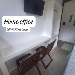 twee stoelen naast een muur met een tv bij Alma Surf House in Boicucanga