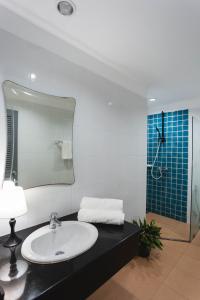 Un baño con lavabo, espejo y ducha. en The One Apartment, en Rawai Beach