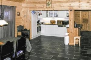 cocina con armarios blancos y suelo de baldosa negra en Coazy cabin with sauna, en Trysil