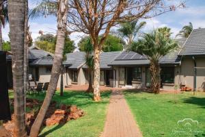 a house with palm trees in the yard at Palmera Guest House in Krugersdorp
