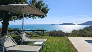 two chairs and an umbrella next to the water at "Quercia House", inside a Private Park, shared Pool, Tennis, AC, Parking next home and a Garage in Lerici! in Lerici +45 photos