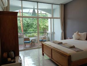 a bedroom with a bed and a large window at Little Jasmine by the River in Phitsanulok