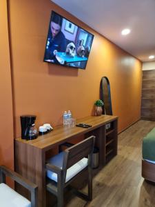 Una habitación con un escritorio y un televisor en la pared. en Condesa Cibel, en Ciudad de México