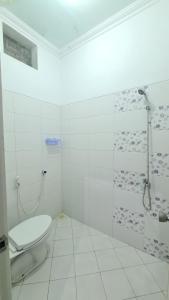 a white bathroom with a toilet and a shower at Rumah Sri Pasti in Jrebeng-wetan