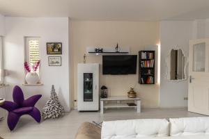 a living room with a white couch and a tv at Ferienwohnungen Vogelnest zentral in Mühlhausen mit Pool in Mühlhausen
