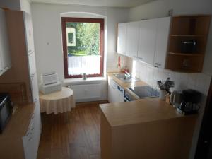 フレンスブルクにあるFerienwohnung Parkgartenの白いキャビネット、窓、シンク付きのキッチンが備わります。