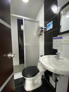 a bathroom with a black toilet and a sink at Hotel HILLS BOGOTA in Bogotá