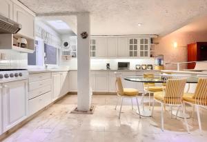 eine Küche mit weißen Schränken und einem Tisch und Stühlen in der Unterkunft Private Villa By Andani in Cancún