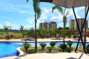 a swimming pool with palm trees and buildings at Praias do Lago Eco Resort - Central de Reservas in Caldas Novas