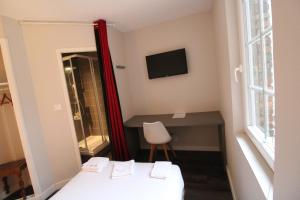 a room with a bed and a desk and a television at Hôtel Casabianca in Moulins