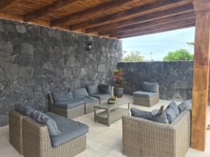 un patio con sofás y una pared de piedra. en Villa Carla, en Playa Blanca