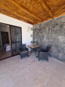 Un patio con mesa y sillas y un muro de piedra. en Villa Carla, en Playa Blanca