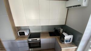 a small kitchen with white cabinets and appliances at Apartament - U Alicji in Konin +8 photos