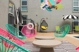 オースティンにあるModern Condo with Pool Gym Workspaces & BBQのカラフルな椅子とテーブル、パラソル付きのパティオ