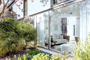 a glass extension of a house with a garden at Blueberry Living - Wohlfühl-Apartment Starnberger See, Design, Sport & Natur in Tutzing