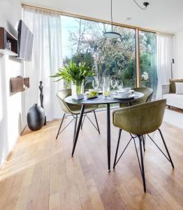 a dining room with a table and chairs in a living room at Blueberry Living - Wohlfühl-Apartment Starnberger See, Design, Sport & Natur in Tutzing