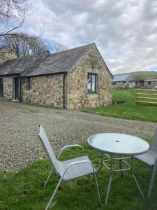 una mesa y sillas frente a un edificio de piedra en Little Barn, en Bodmin