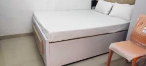 a small bed in a room with a chair at Hotel O Home Crystal Cottage Home Stay in Ayodhya