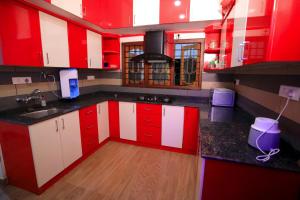 a kitchen with red and white cabinets and wooden floors at Hillsidecreek Homestay in Anachal
