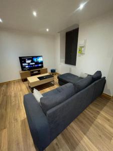 Una sala de estar con un sofá azul y un televisor de pantalla plana. en Maison du Tripot, en Ligny-en-Barrois
