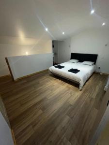 Un dormitorio con una cama y suelo de madera. en Maison du Tripot, en Ligny-en-Barrois