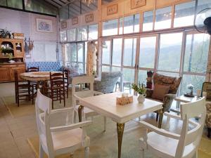 jadalnia ze stołem, krzesłami i oknami w obiekcie Balmy Hideout Cafe'& Homestay w mieście Ban Huai Kaeo