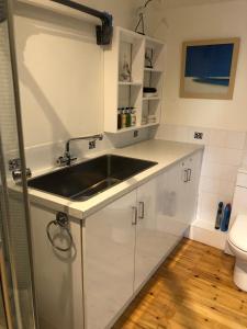 a white kitchen with a sink and a toilet at The Nook in Padstow +32 photos