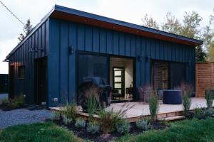 a blue shed with a wooden deck in a yard at Reid's Cove Retreat in Tatamagouche