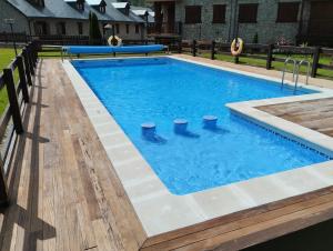 a swimming pool with blue water and a wooden deck at El rincón de Benás in Anciles +35 photos