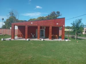 a small red brick building with a grass field at La casita de duggan in Duggan