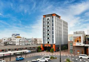 a tall building with cars parked in a parking lot at APA Hotel Saitama Higashimatsuyama Ekimae in Higashimatsuyama