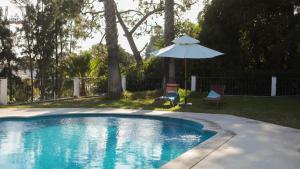 a swimming pool with an umbrella and two chairs and a table and an umbrella at Villa Casa do Cruzeiro in Estoril