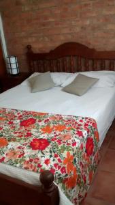 Una cama con una manta floral encima. en Guardalaola en Las Grutas