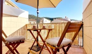 a table and chairs on a balcony with an umbrella at La Casita de Benatae in Benatae