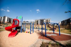 a playground with a red slide in a park at K47 propertyzz in Midrand