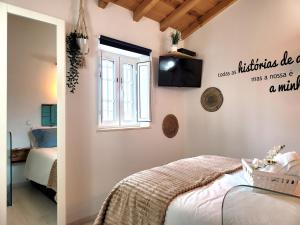 a bedroom with a bed and a television on the wall at Casinha da Esquina - Refúgio Alentejano a 700m da Praia in Amieira
