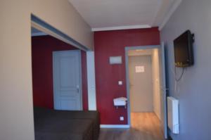 パリにあるオテル アレティの赤い壁のベッドルーム1室、テレビ付きのドア1室