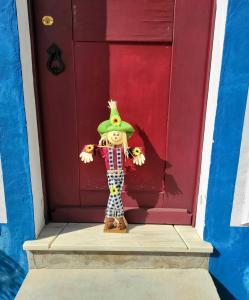 a doll standing in front of a red door at Casa da Chaminé - A Casa da Chaminé "torta" in Amieira
