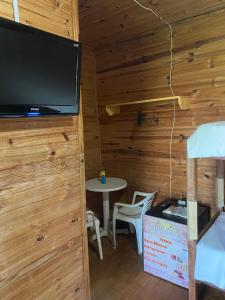una camera con TV e tavolo in una cabina di Pousada Casa de Madeira a Porto De Galinhas
