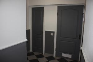 a hallway with two black doors and a checkered floor at Lemberg Elite Apartments in Lviv