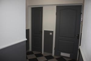 リヴィウにあるLemberg Elite Apartmentsの黒いドアが2つあり、チェックした床が備わる廊下